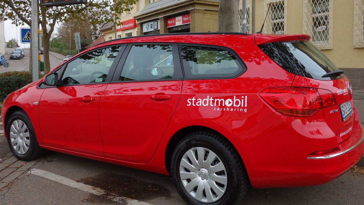 rotes Fahrzeug von Stadtmobil vor dem Asperger Bahnhof